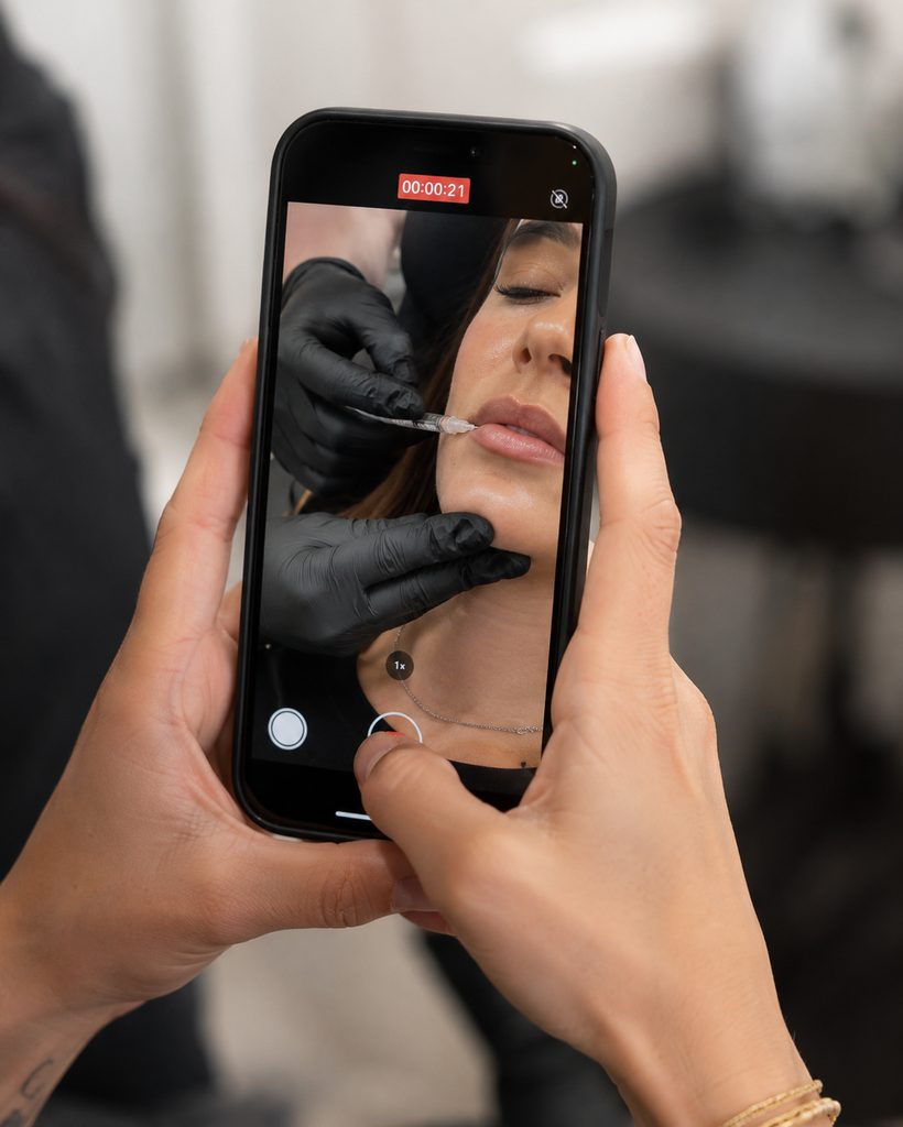 Filming a lip treatment on a phone at a med spa for a social media reel